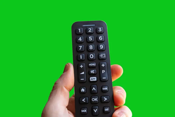 Krom anahtarı için yeşil ekran arka planında izole edilmiş bir uzaktan kumandayı tutan el..