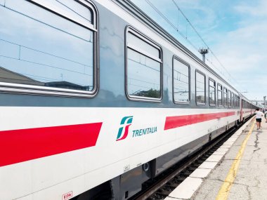 Bir İtalyan Trenitalia treninin vagonu platformda durdu ve yazın arka planda bekleyen insanlarla birlikte ayrılmayı bekledi.. 