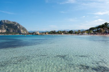 Mondello Körfezi ve sahilinde yaz güneşinde turistler ve şeffaf mavi deniz. Sicilya 'da tatil yeri, Palermo plajı. İtalya. İtalyan denizi. Akdeniz.