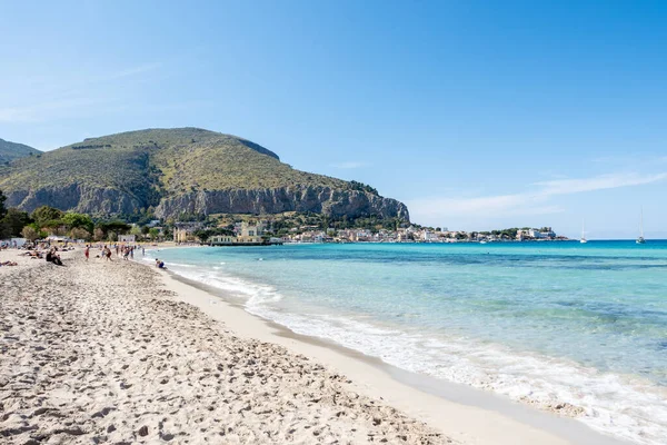 Italy, blue sea and sand beach. Mondello sand beach with tourists in the summer turquoise transparent blue sea and sunny sky. Vacations in Sicily, Palermo, Italy. Italian sea. Mediterranean see