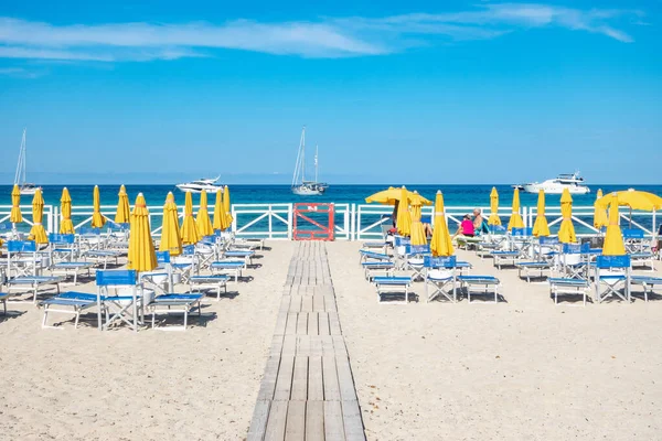 stock image Mondello sand beach with closed colored beach umbrellas in the summer sun and transparent turquoise blue sea  and sailing boats. Vacation spot in Sicily, Palermo beach. Mondello, Palermo, Italy 