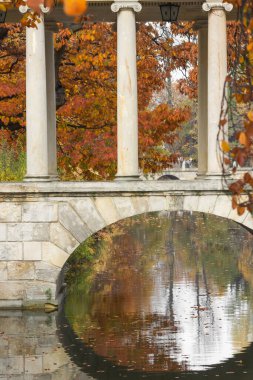 Kanalın üzerindeki beyaz köprünün bir kısmı adadaki saraya giden sütunlar, Lazienki Parkı 'ndaki Kraliyet Sarayı - Varşova. Polonya 'nın Varşova kentinde Sonbahar Lazienki veya Kraliyet Hamamları parkı.