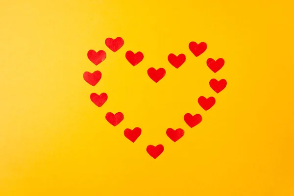 stock image The heart form is made up of many red paper hearts isolated on yellow background. Valentine's day concept. High quality photo