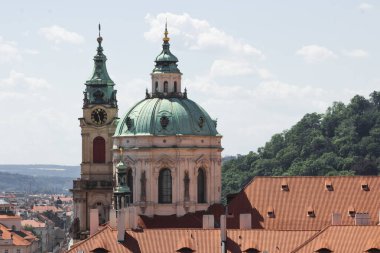 Çek Cumhuriyeti Prag 'daki Mala Strana bölgesinde saat kulesi olan eski Aziz Nicholas kilisesi. Prag 'ın eski kasabasının şehir manzarası. Kırmızı kiremitli çatılar, katedral kubbesi ve şehir parkı.