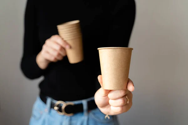 stock image Woman in black shirt holding paper cup of craft paper. Tea, coffee, matcha to go. Zero waste material. Ecology and recycling concept.