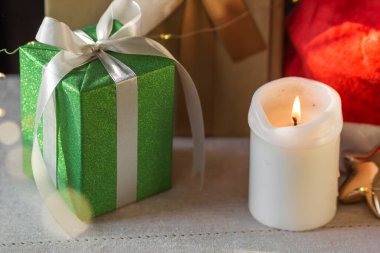 Yeni yıl ya da Noel kompozisyonu paketlenmiş hediye kutuları, yanan mum ve Noel Baba şapkası. Çelenk renkli Xmas titreşimleri. Kış tatiline hazırlık. Noel alışverişi ve satışları. 