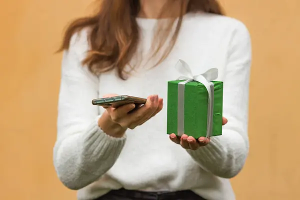 Mãos Mulher Segura Smartphone Caixa Presente Verde Com Arco Isolado — Fotografia de Stock
