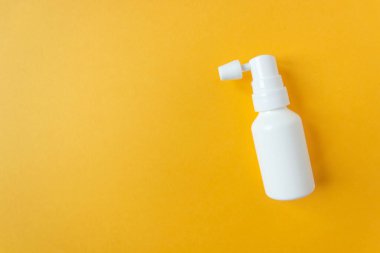 Sarı arka planda hortumu olan beyaz kulak spreyi şişesi. Önlem ve kulaklara dikkat. Mesaj için yer var. Yatay fotoğraf.