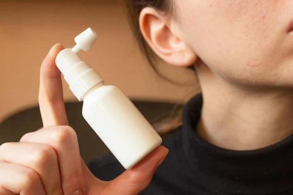White ear spray bottle with nozzle in woman\'s hand. For daily clean the ears from earwax. Woman\'s hygiene and health care. Horizontal photo. Close-up.