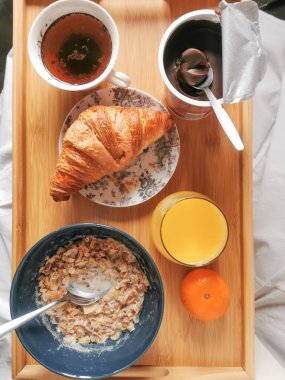 Sabah rutini, tam kahvaltı yulaf ezmesi, bir bardak portakal suyu, taze fırın, bir kaşık boğaz otu ezmesi ve bir fincan kahve. Katlanmış ahşap masa. Genel Görünüm.