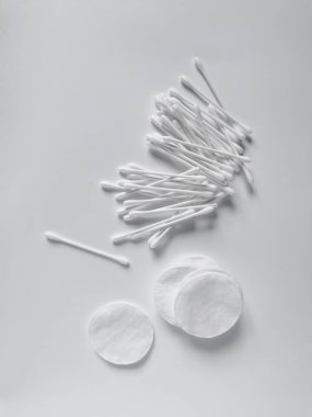 White cotton swabs and pads for daily feminine hygiene and care for the face and ears. Flat lay composition on the white background.