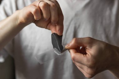 Man's hands holds black nose patch in front of him, ready for use. Married male using cosmetics to clean pore skin and remove blackheads on nose. Daily morning routine and skin care concept. 