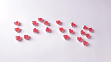 Womans hand adds the missing element to the word love. Jelly candies in hearts form. Romantic message for lovers. Valentines Day concept. High quality FullHD footage