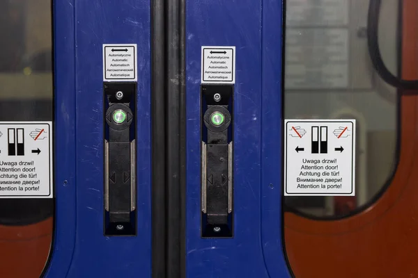 Door of train carriage or subway car with the electric green button press to open sliding automatical doors between the passenger wagons. Train door push button. Public transport regulations concept.