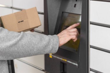 Pniewy, Polonya - 22 Mart 2023. Yaşlı kadınların el kodlarını açıp bir paket göndermek için posta kutusuna el koyuyorlar. E-ticaret nakliyat ve teslimat konsepti. Modern teknoloji.