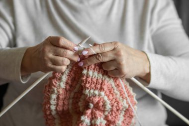 Şırıngalarla örgü ören yaşlı kadınlar bereli şapkalar. Büyükanne pembe ve beyaz doğal yün ipliklerle örer, en sevdiği hobiyi sever. El yapımı yün. Yapı ve DIY kavramı.