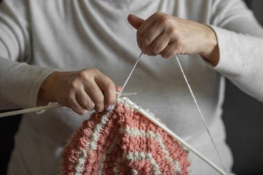 Şırıngalarla örgü ören yaşlı kadınlar bereli şapkalar. Büyükanne pembe ve beyaz doğal yün ipliklerle örer, en sevdiği hobiyi sever. El yapımı yün. Yapı ve DIY kavramı.