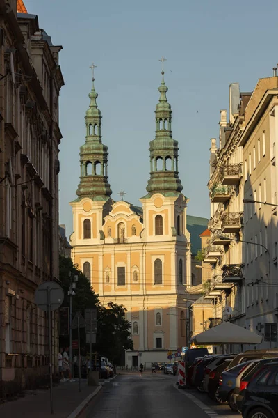 stock image Poznan, Poland - June 12, 2023: view of Dluga street with St. Francis Seraphim church during sunset, golden hour. Historical architecture in old town. Two towers of St. Francis Seraphim church.