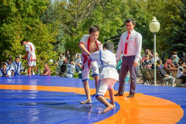 Almaty, Kazakistan - 18 Eylül 2022. Kimonolu iki genç güneşli bir günde şehir parkında güreş müsabakalarına katılıyorlar.