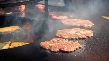 Hamburger köfteleri, bir fast food restoranının ızgarasında kızartılmış tabakta dumanla pişirilir..