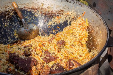Açık ateşte büyük bir kazanda pişirilmiş etli pilav. sokak yemekleri
