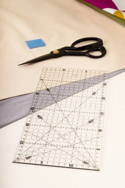 Kumaş kesimlerinin arka planına karşı cetvel, tebeşir ve makas.