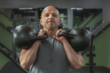 Spor salonunda su ısıtıcılarıyla egzersiz yapan kaslı bir adam. Yakın plan.