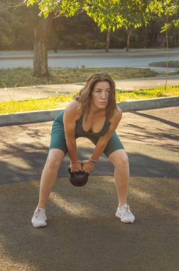 Genç Kafkasyalı kadın sokak spor sahasında bir çaydanlıkla egzersiz yapıyor. Sağlıklı yaşam tarzı