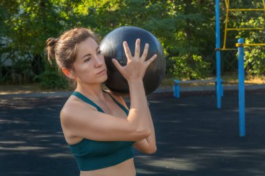 Çekici beyaz kadın, bir sokak sporu sahasında ilaç topuyla egzersiz yapıyor. Sağlıklı yaşam tarzı