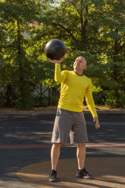 Adam bir sokak sporu sahasında ilaç topuyla egzersiz yapıyor. Sağlıklı yaşam tarzı