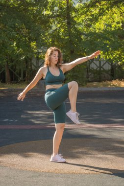 Genç bir kadın sokak sporlarında bacak hareketlerini sergiliyor. Sağlıklı yaşam tarzı