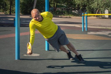 Sporcu güneşli bir günde tek eliyle sokak sporları alanında şınav çeker. Sağlıklı yaşam tarzı