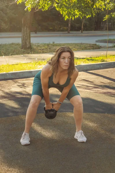 Genç Kafkasyalı kadın sokak spor sahasında bir çaydanlıkla egzersiz yapıyor. Sağlıklı yaşam tarzı