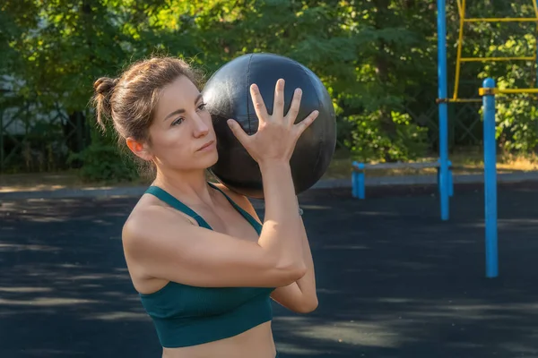 Çekici beyaz kadın, bir sokak sporu sahasında ilaç topuyla egzersiz yapıyor. Sağlıklı yaşam tarzı