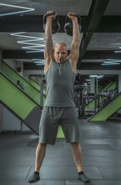 Erkek sporcu spor salonunda ağırlık kaldırır.