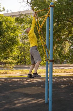 Adam sokak sporları alanında bir kaya tırmanma makinesinde eğitim görüyor. Sağlıklı yaşam tarzı