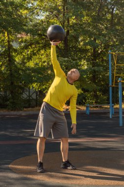 Adam bir sokak sporu sahasında ilaç topuyla egzersiz yapıyor. Sağlıklı yaşam tarzı