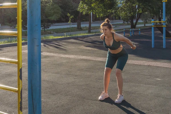 stock image Young caucasian woman exercising with a rubber expander on a street sports ground