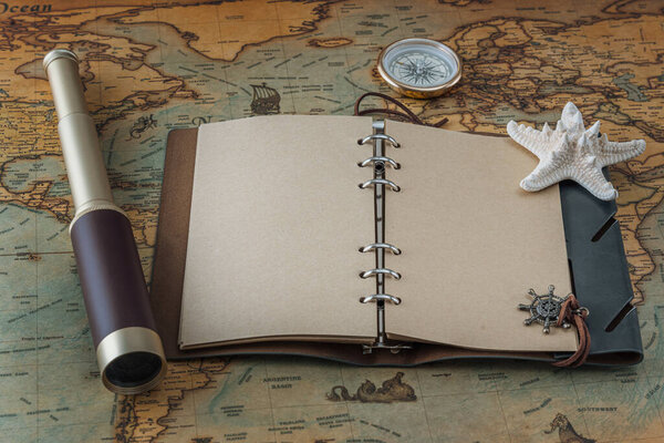 Открыть кожаную книгу с пустыми страницами для написания текста или логотипа, шпионского стекла, морской звезды и латунного компаса лежат на винтажной карте