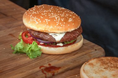 Tahta bir tahtanın üzerinde sıradan bir sokak hamburgeri. Sokak yemeği. Yakın plan.