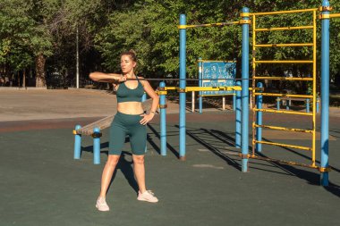 Beyaz bir kadın sokak sporları alanında lastik genişleticiyle egzersiz yapıyor.