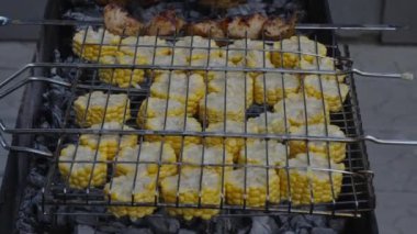 Mısır koçanları açık bir ızgarada kömürde pişirilir. Izgara, barbekü, piknik