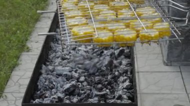 Adamın eli yanan kömürlerin üzerindeki mısır ızgarasını çeviriyor. Izgara, barbekü, piknik