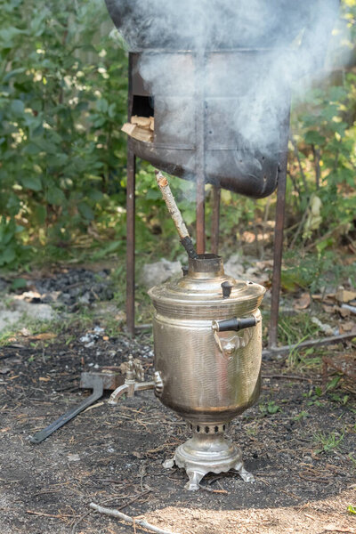 дровяной котел для нагрева воды с помощью дымящейся трубы - самовар на открытом воздухе