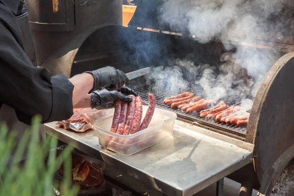 Process of preparing hot dog sausages on a grill with burning coals. Street eatery