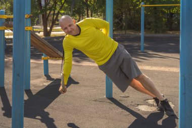 Sporcu güneşli bir günde tek eliyle sokak sporları alanında şınav çeker. Sağlıklı yaşam tarzı