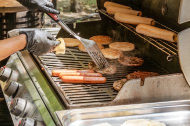 Hamburgerler ve çizburgerler için et pişirme, sosisliler için sosis, kömürlü ızgarada çörekler. Sokak yemeği.