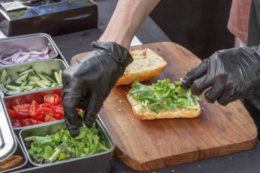 Şef, hamburger ya da sandviç yapmak için marul yapraklarını ekmek dilimine koyar. sokak yemekleri
