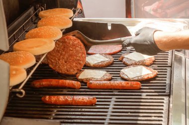 Hamburgerler ve çizburgerler için et pişirme, sosisliler için sosis, kömürlü ızgarada çörekler. Sokak yemeği.