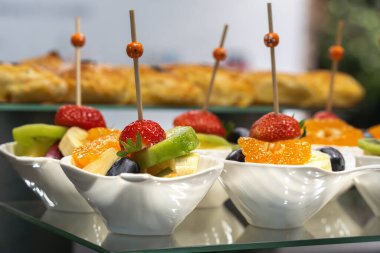 Cam bir masada açık büfe için hazırlanmış beyaz bir kasede meyve salatası. Yakın plan.